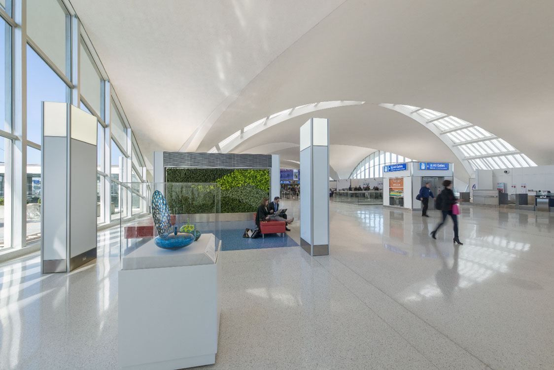 The interior of an airport with people walking around.