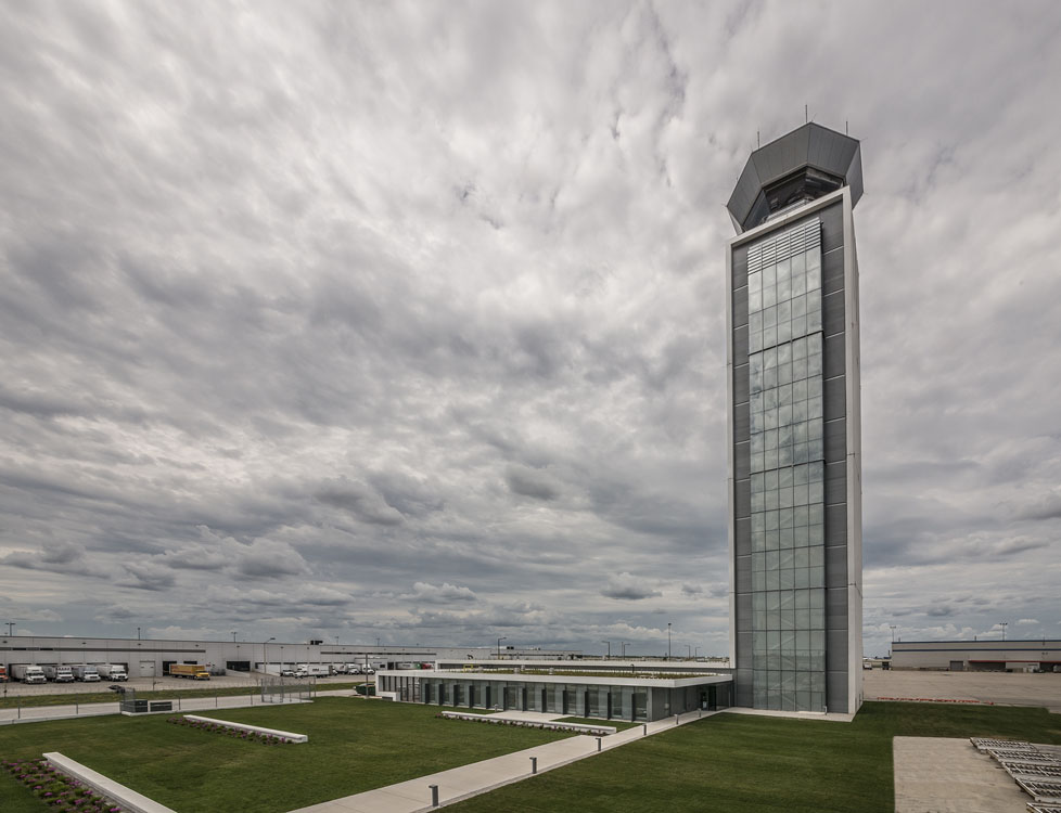 An airport control tower with a cloudy sky.