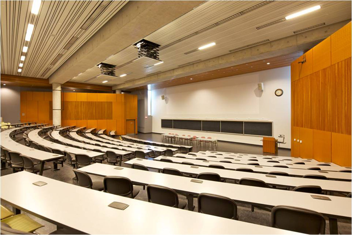 A lecture hall with rows of tables and chairs.