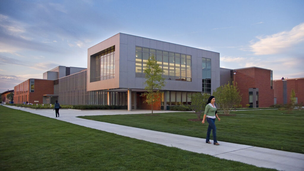 A woman walks down the sidewalk in front of a building.