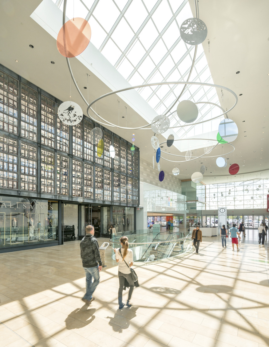 People walking through a lobby with a large glass ceiling.