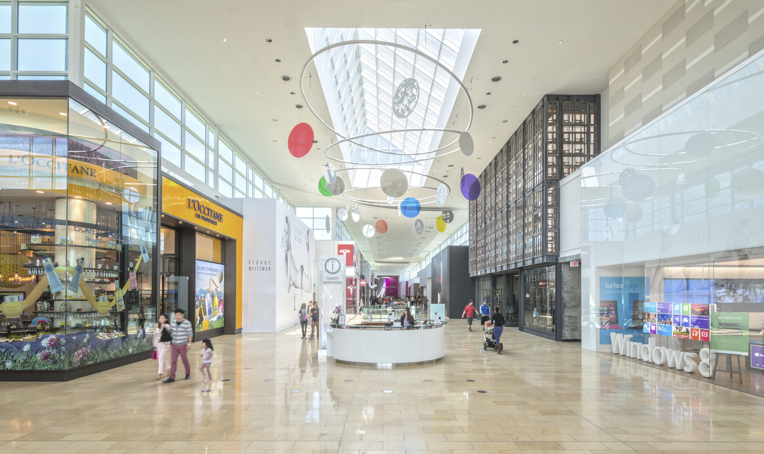 The interior of a shopping mall with people walking around.