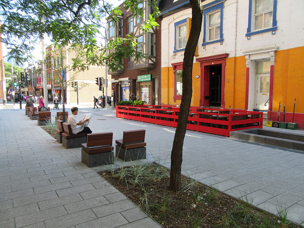 A woman is reading a book on a bench in front of a building.