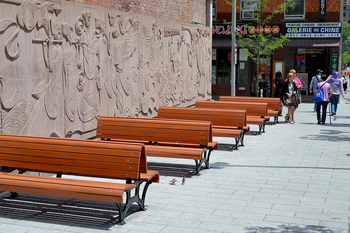 A row of wooden benches on a sidewalk.