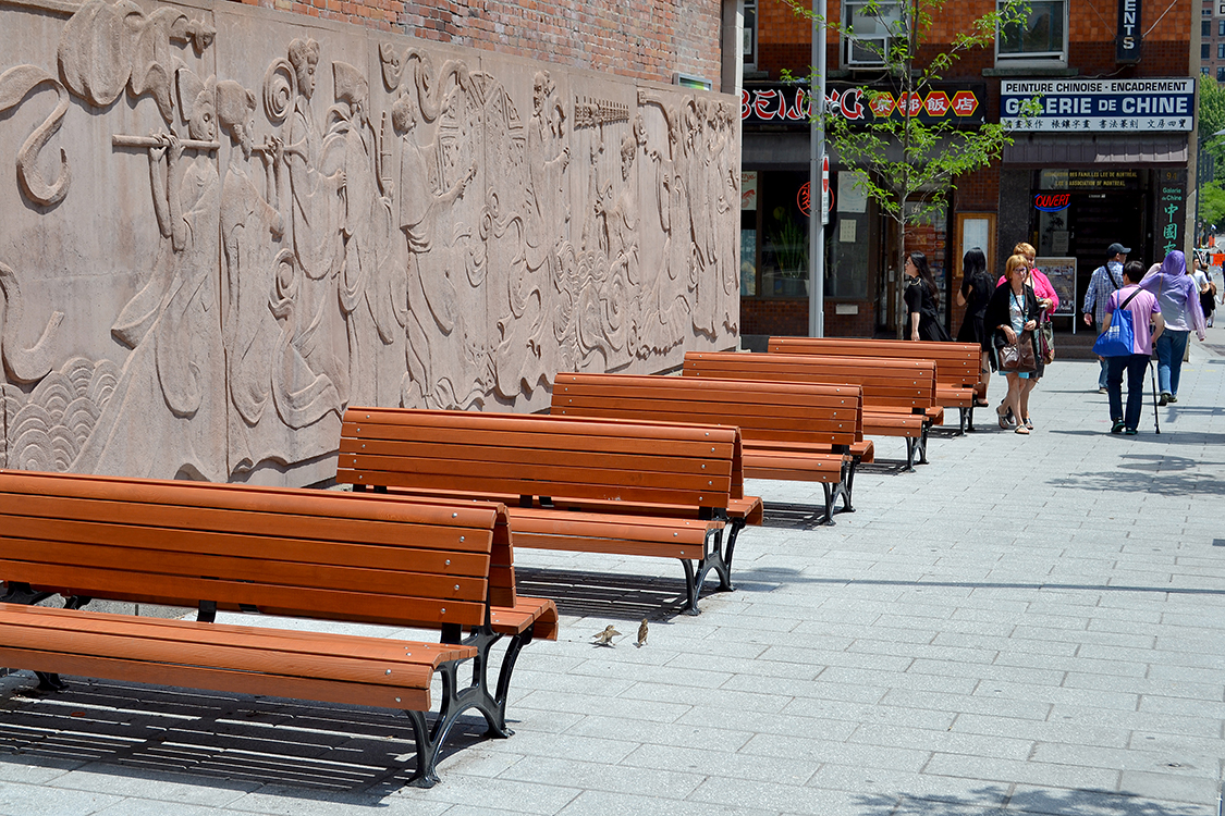 Une rangée de bancs en bois sur un trottoir.