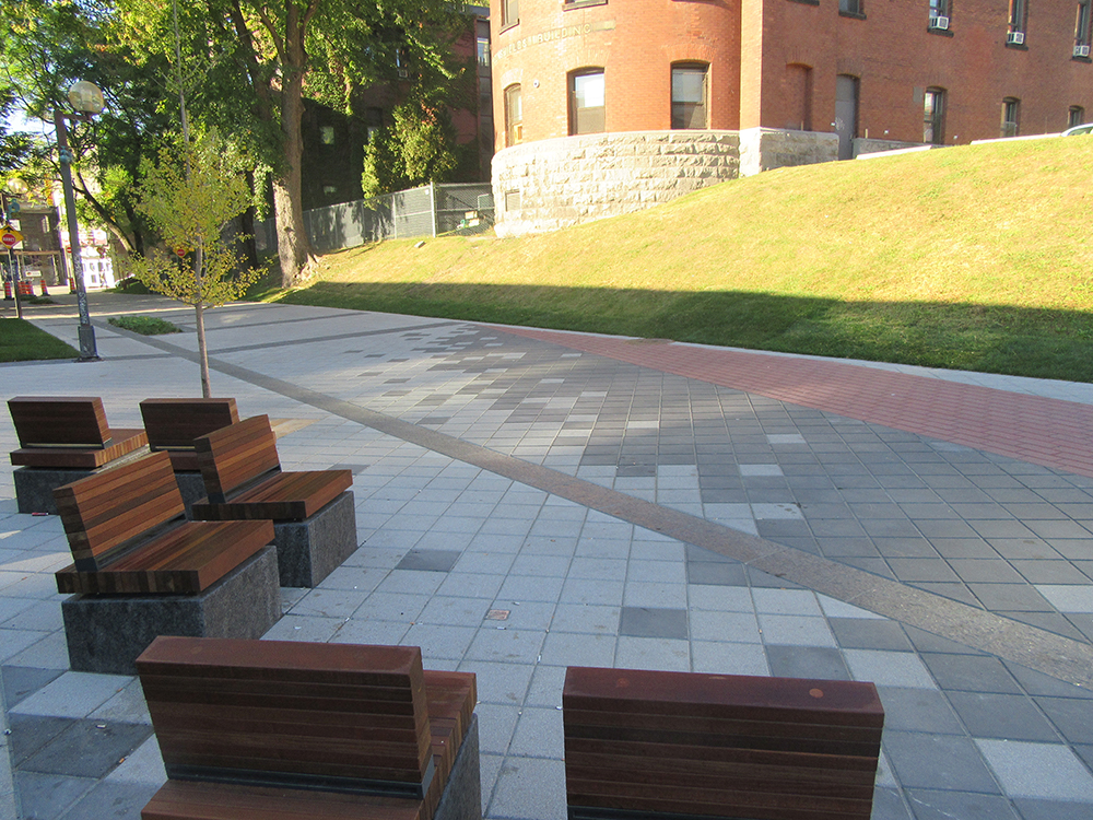 A group of benches on a sidewalk in front of a building.