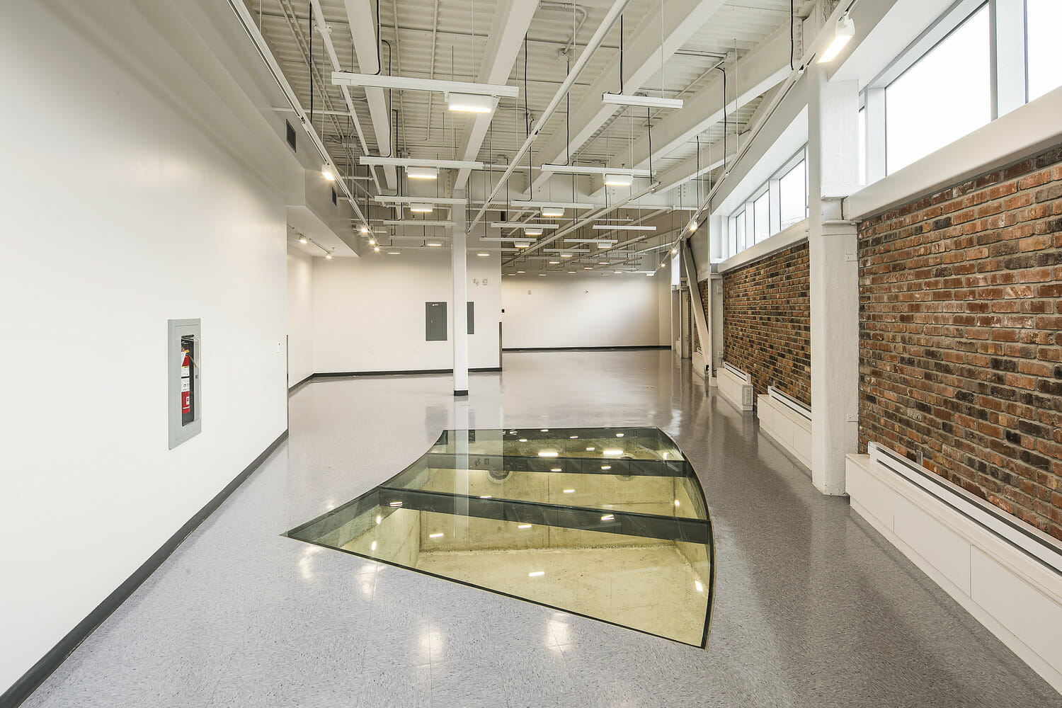 A hallway with a glass floor and a brick wall.