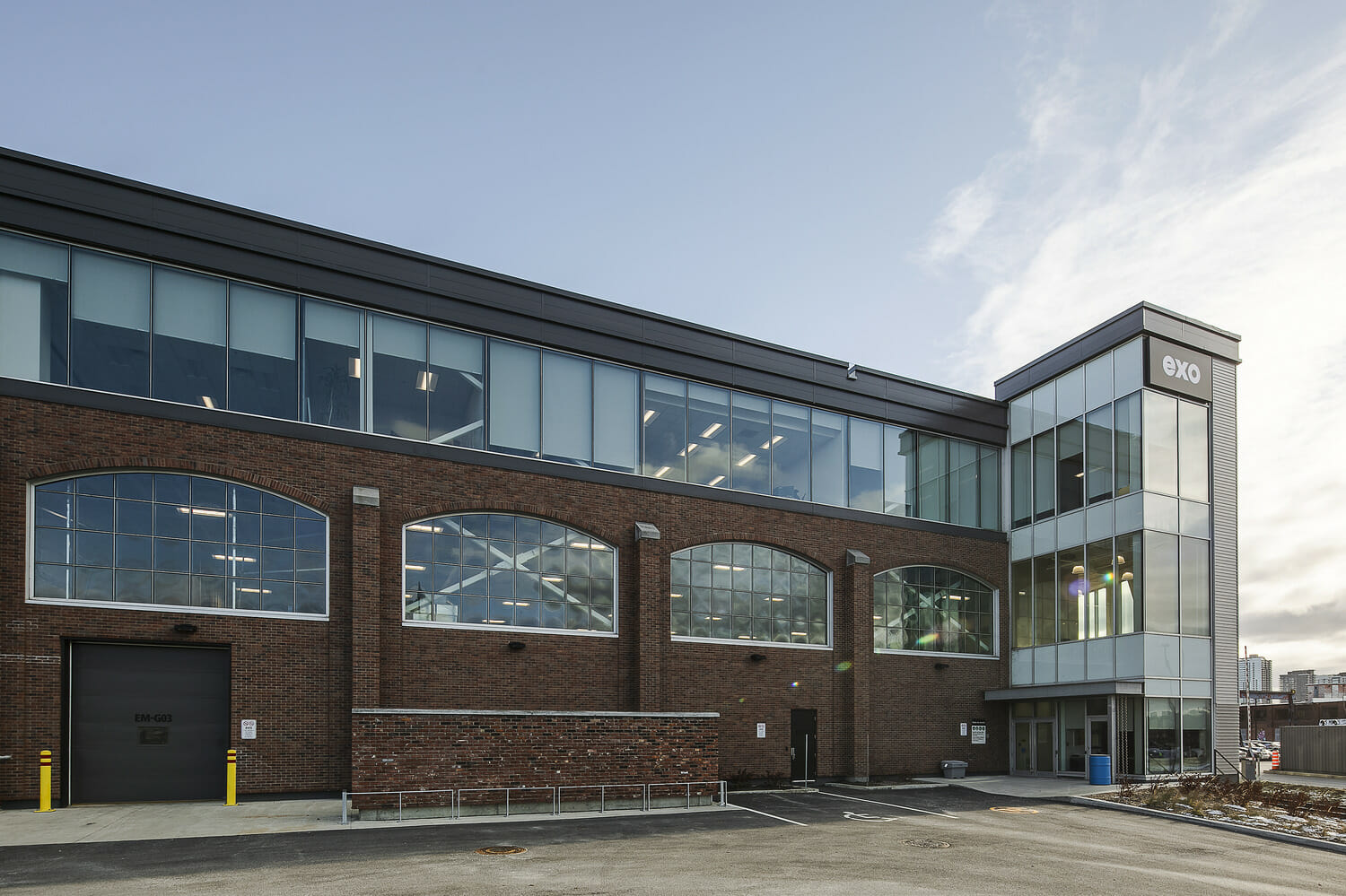 A brick building with glass windows and a parking lot.