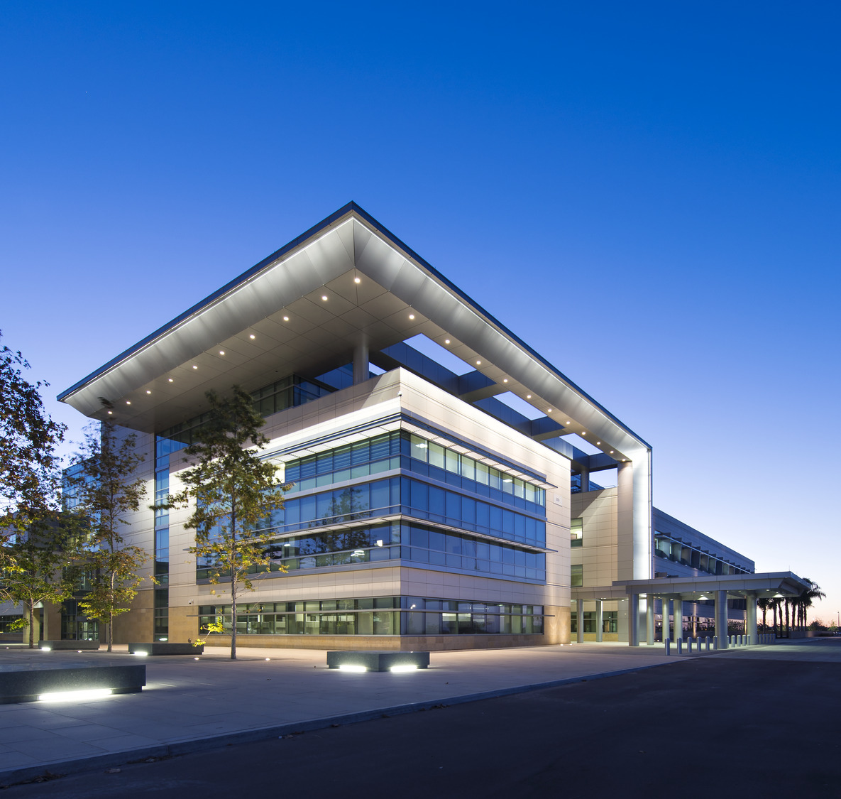 A modern office building lit up at dusk.