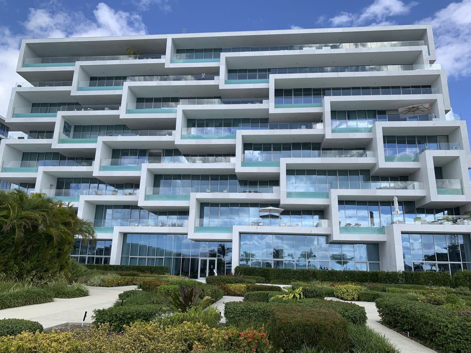 A large building with balconies and bushes in front of it.