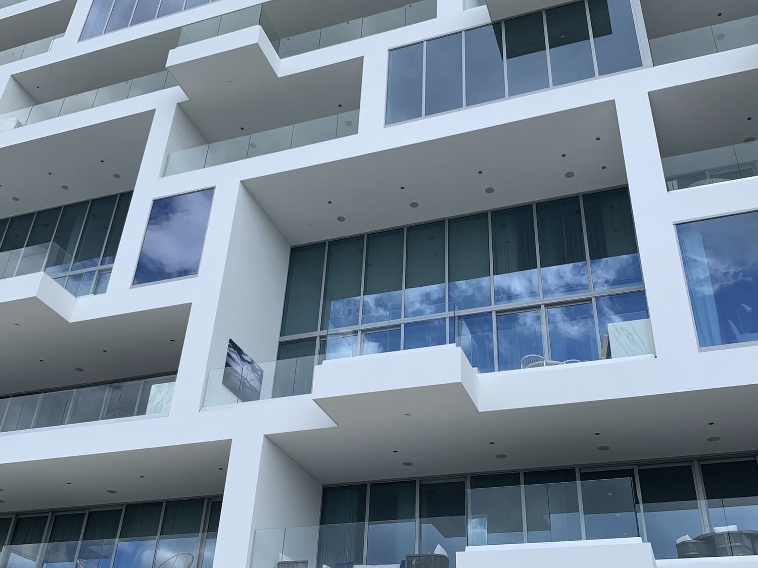 Rendu 3D d'un bâtiment blanc avec balcons et fenêtres.