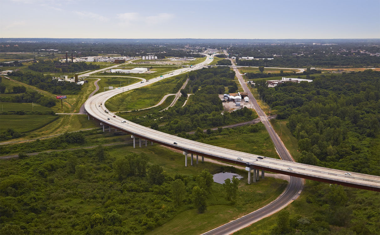 An aerial view of a highway over a green field.