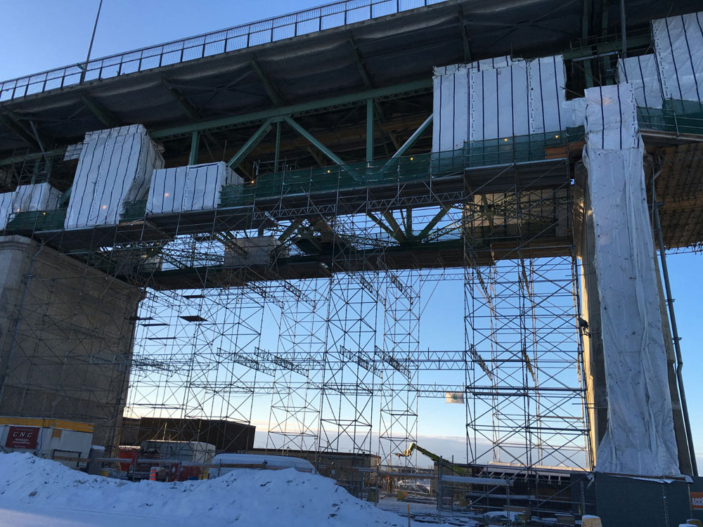 A bridge under construction with scaffolding and snow on it.