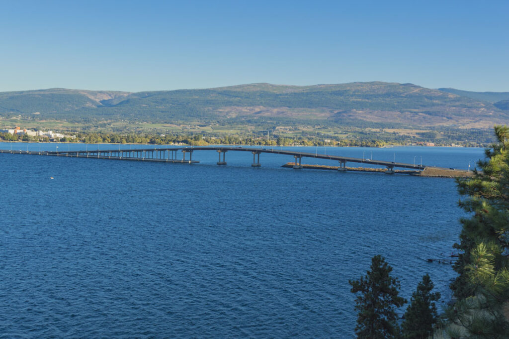 A bridge over a body of water with mountains in the background.