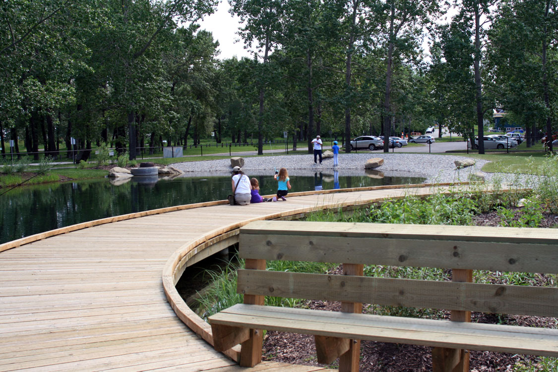 A wooden walkway leading to a pond.