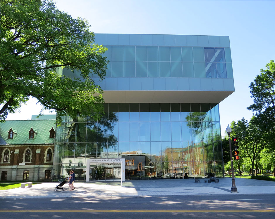 Un grand bâtiment en verre avec des gens qui marchent devant.