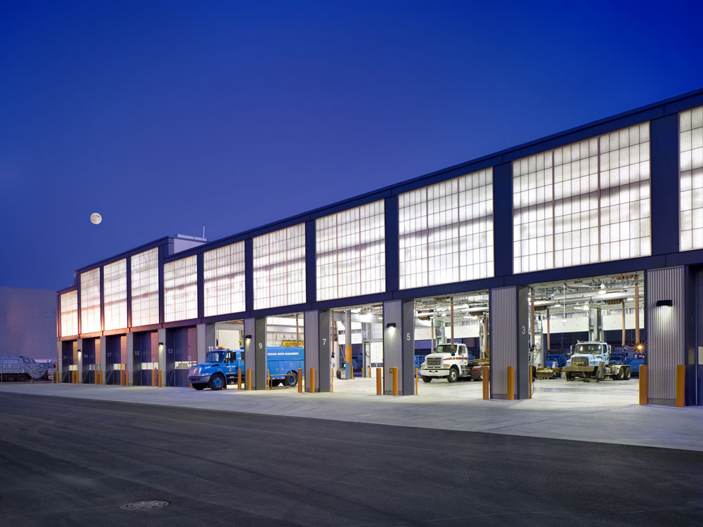 A warehouse with trucks parked in front of it at night.