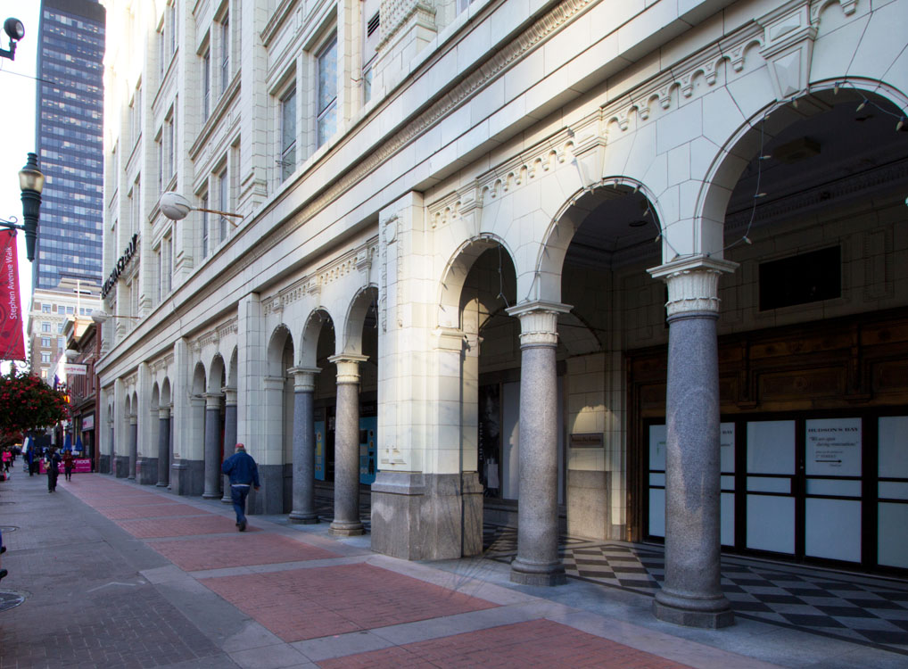 A sidewalk with columns and a building in the background.