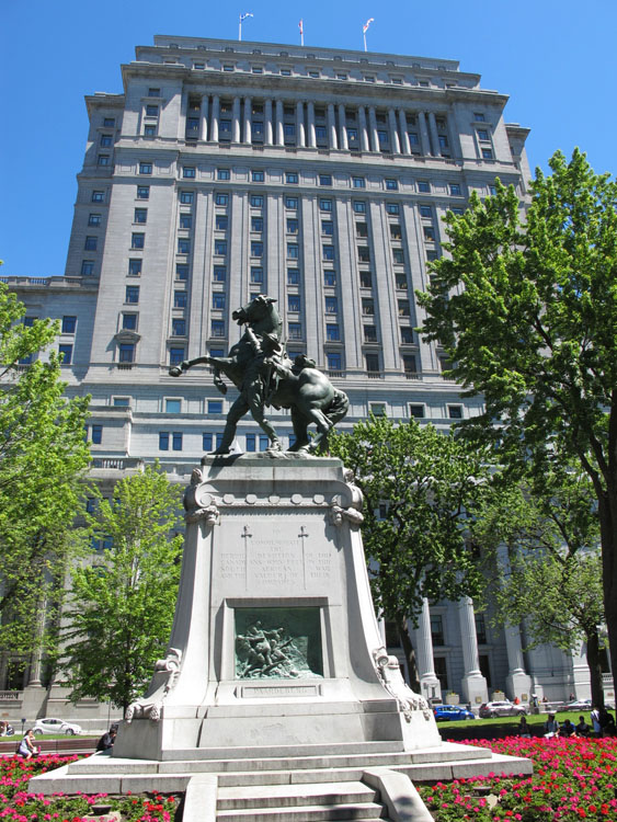 Une statue d'un homme montant à cheval devant un immeuble.
