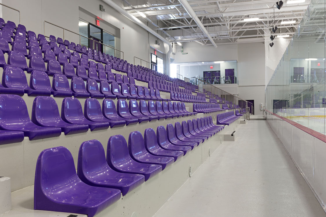 A row of purple seats in a hockey rink.