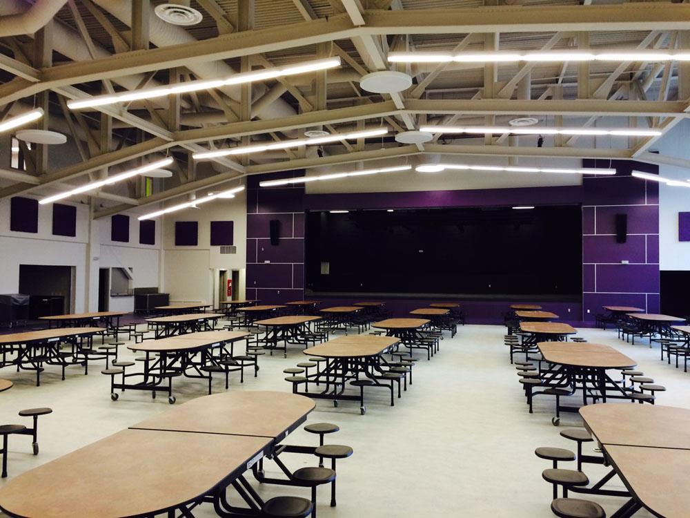An empty gymnasium with tables and chairs.