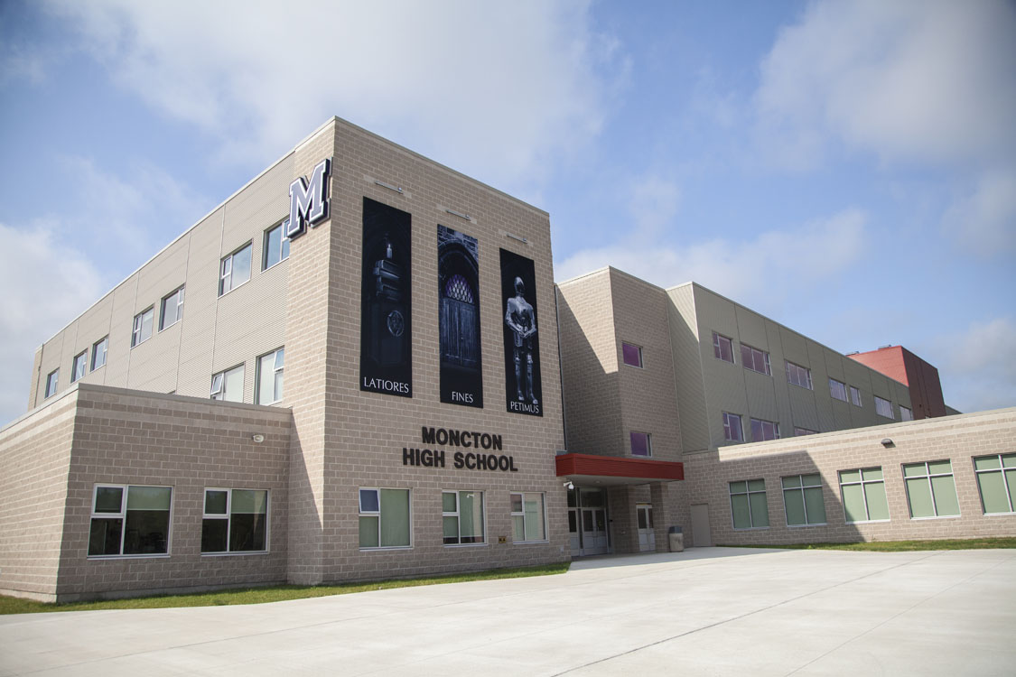 The front of a school building with a sign on it.