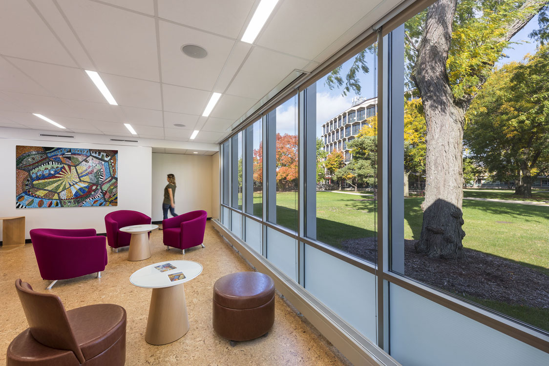 A lobby with purple chairs and windows overlooking a park.