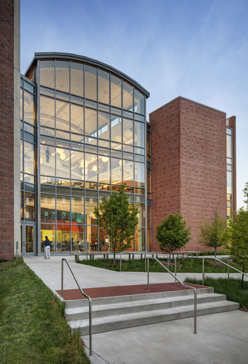 A building with glass windows and steps leading to a grassy area.