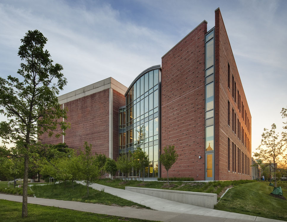 A brick building with trees and grass in the background.