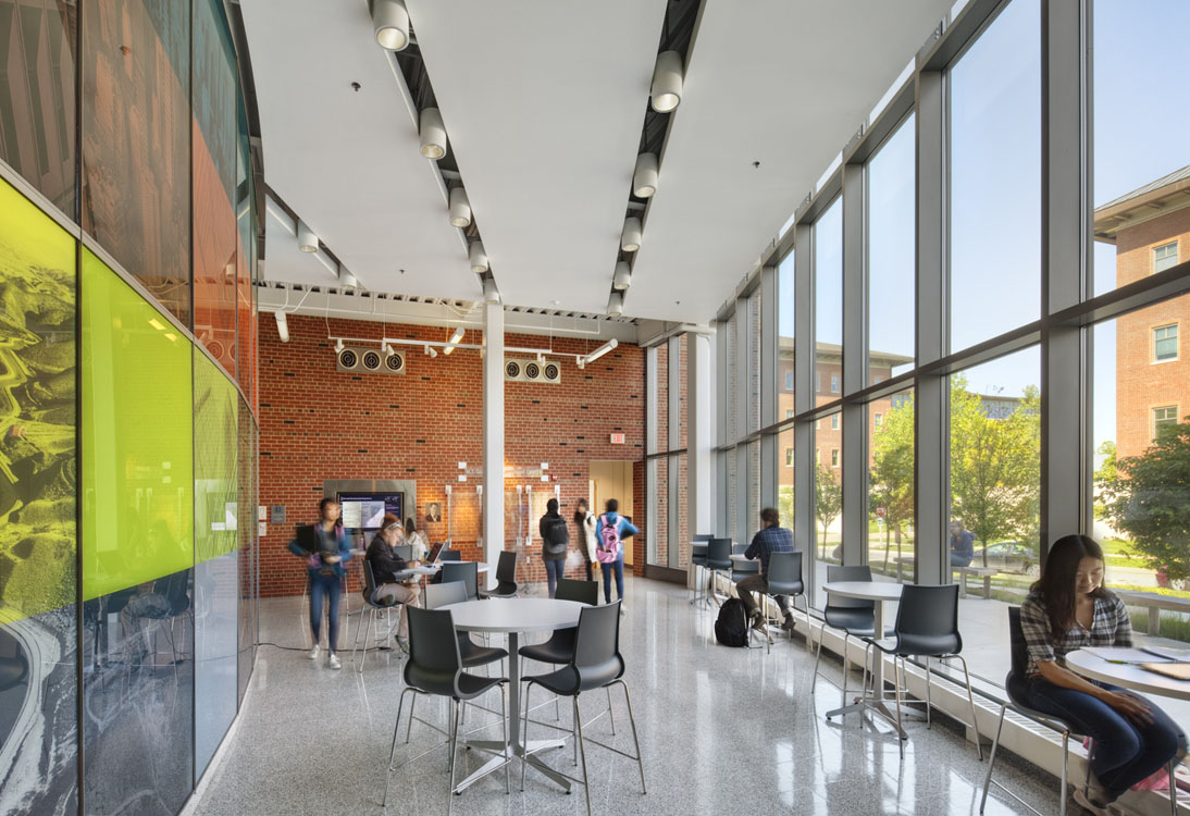 A group of people are sitting in a room with large windows.