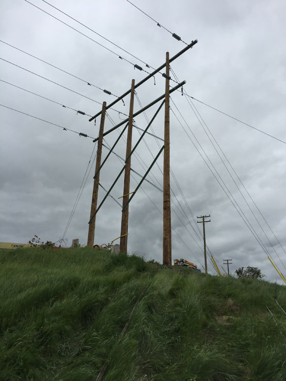 Lignes électriques sur une colline herbeuse.