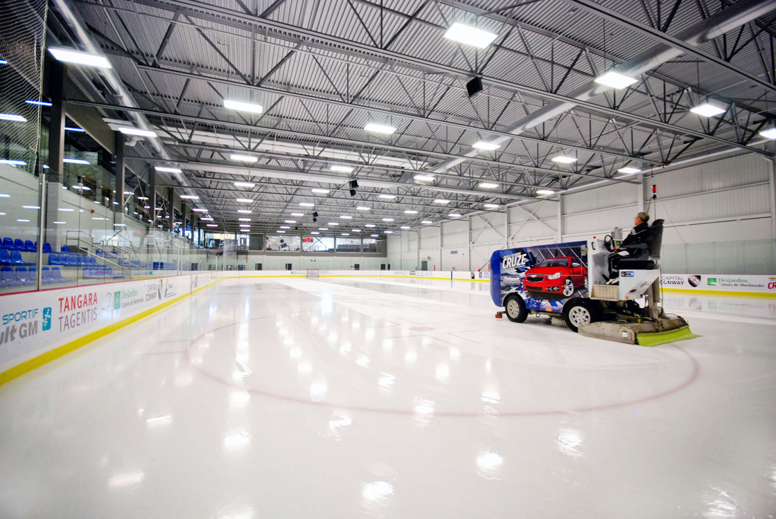 A man is cleaning the ice in an ice rink.