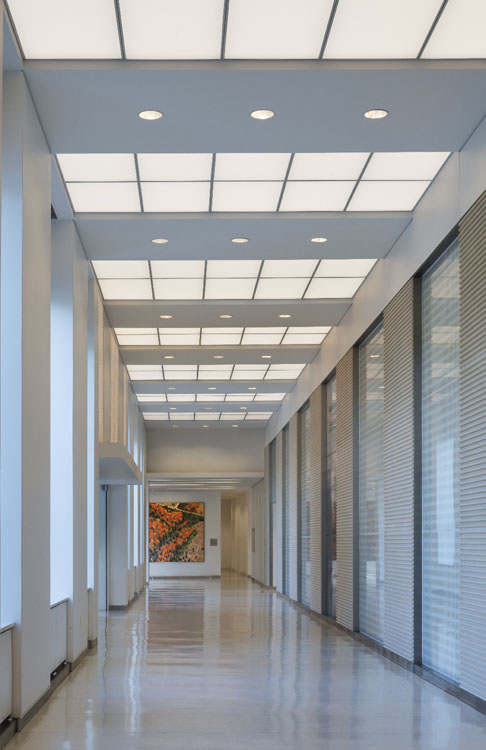 A hallway in a building with white walls and windows.