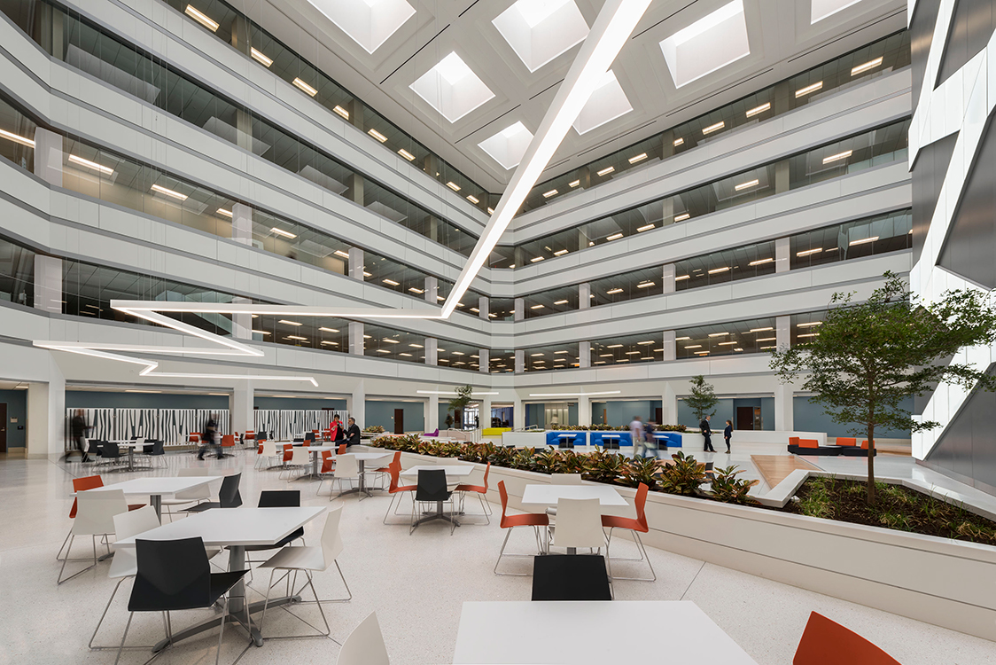 The atrium of a modern office building with tables and chairs.