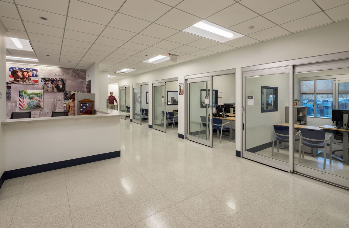 A hallway with glass doors and a computer desk.