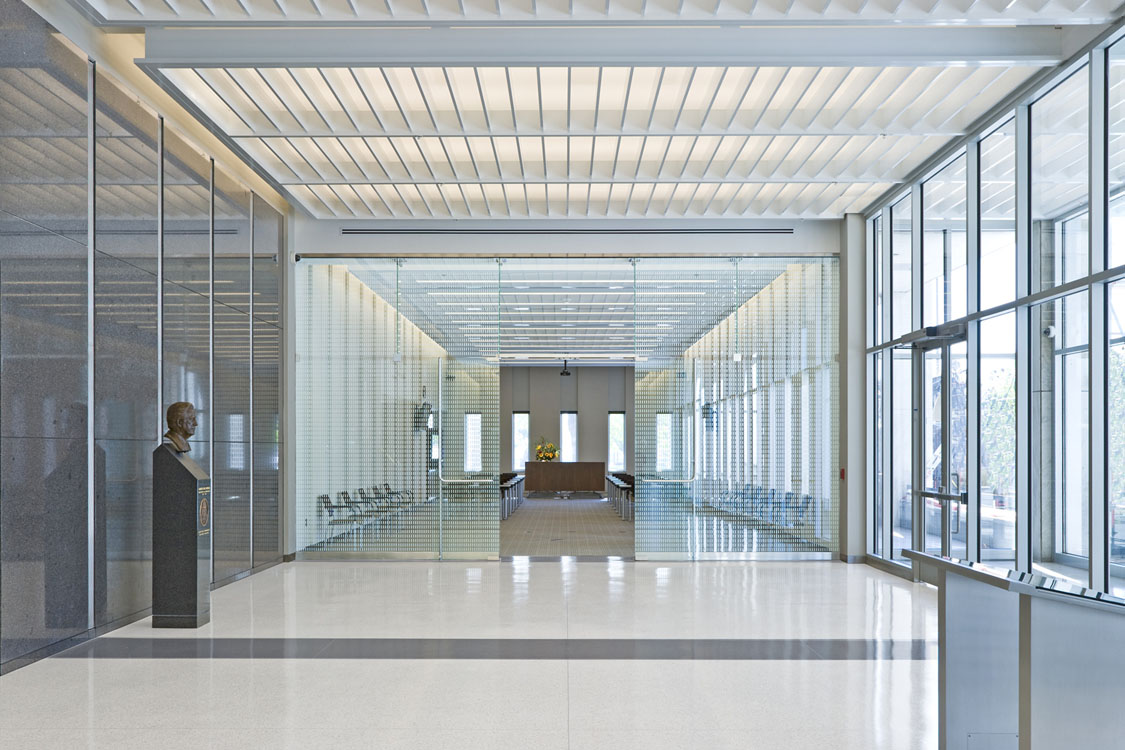 A hallway with glass walls and a statue.