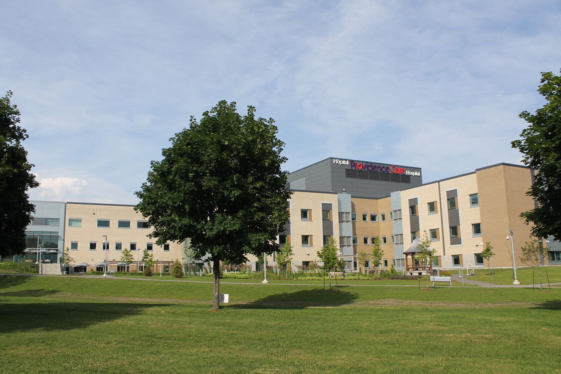 A grassy field with trees and a building in the background.