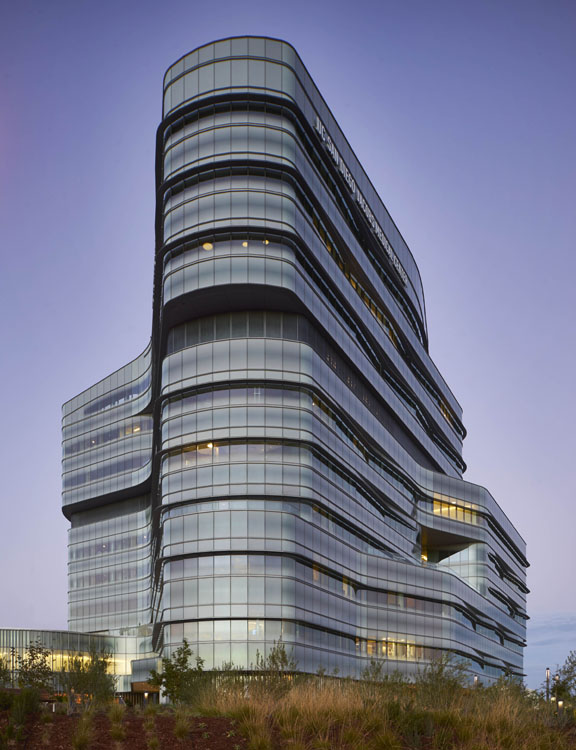 A large glass building on a hillside at dusk.