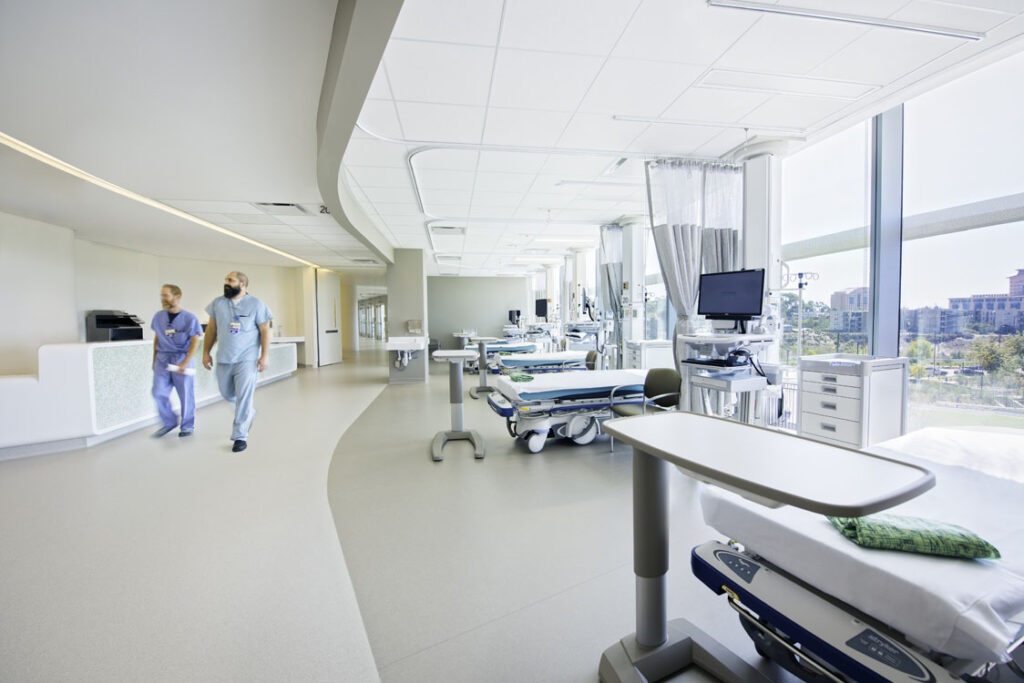 A hospital room with two beds and a large window.