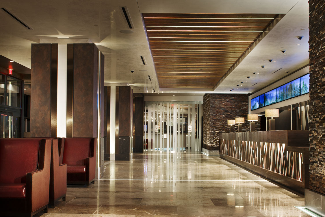 A lobby with red chairs and a stone wall.