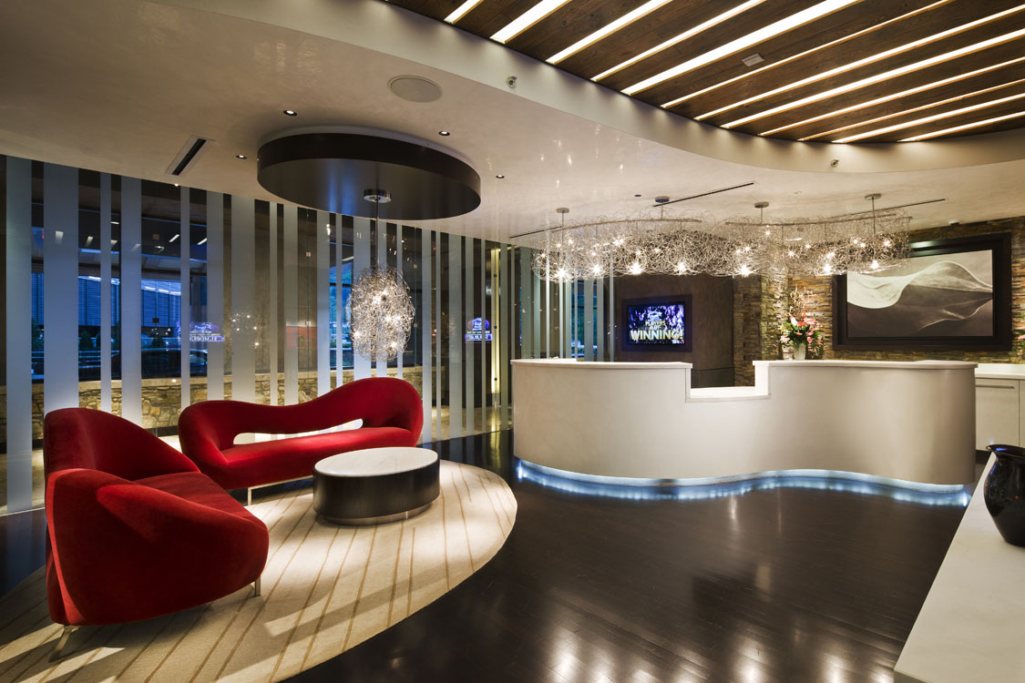 A modern reception area with red chairs and lighting.