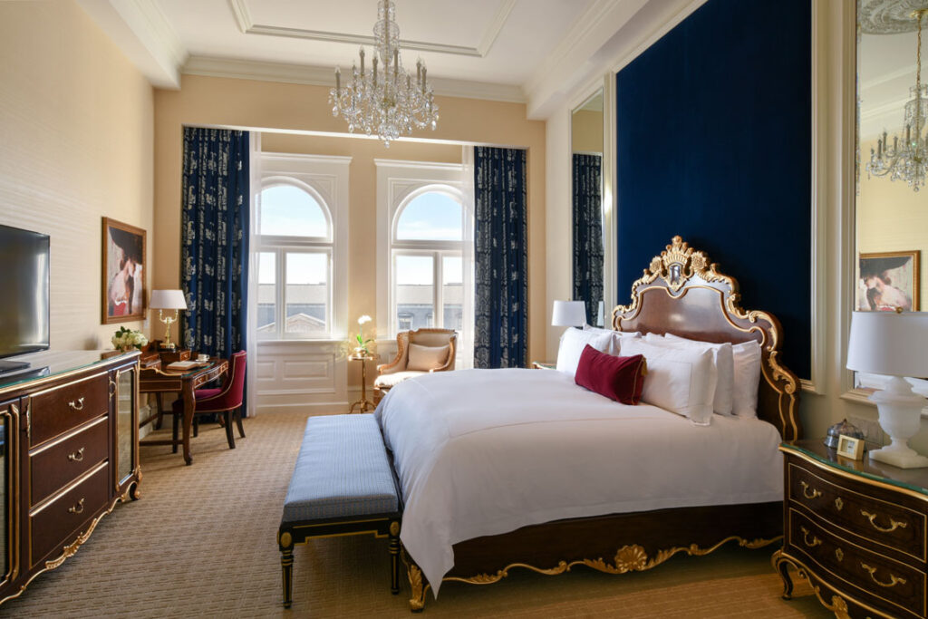 A bedroom with an ornate bed and a chandelier.