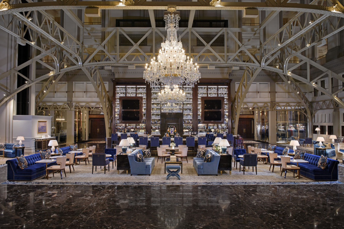 Le hall d’un hôtel avec un lustre et des chaises bleues.