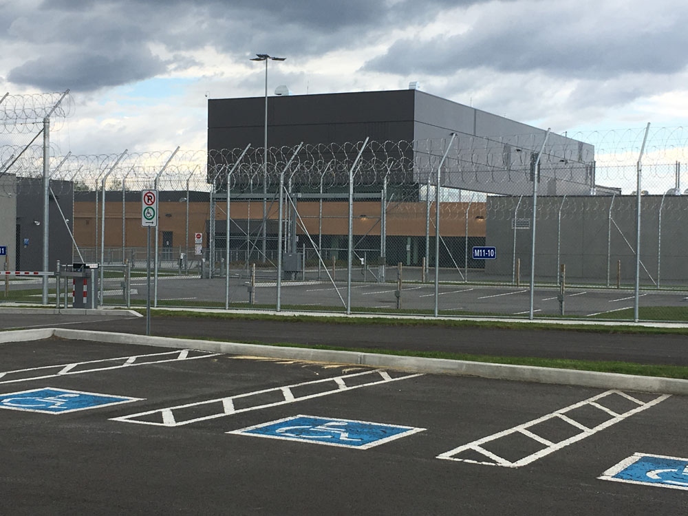 A parking lot in front of a building with a fence.