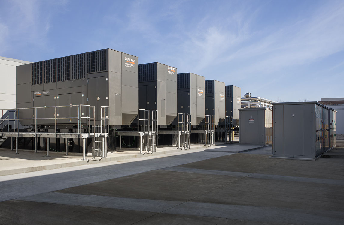 Une rangée d’équipements industriels devant un bâtiment.