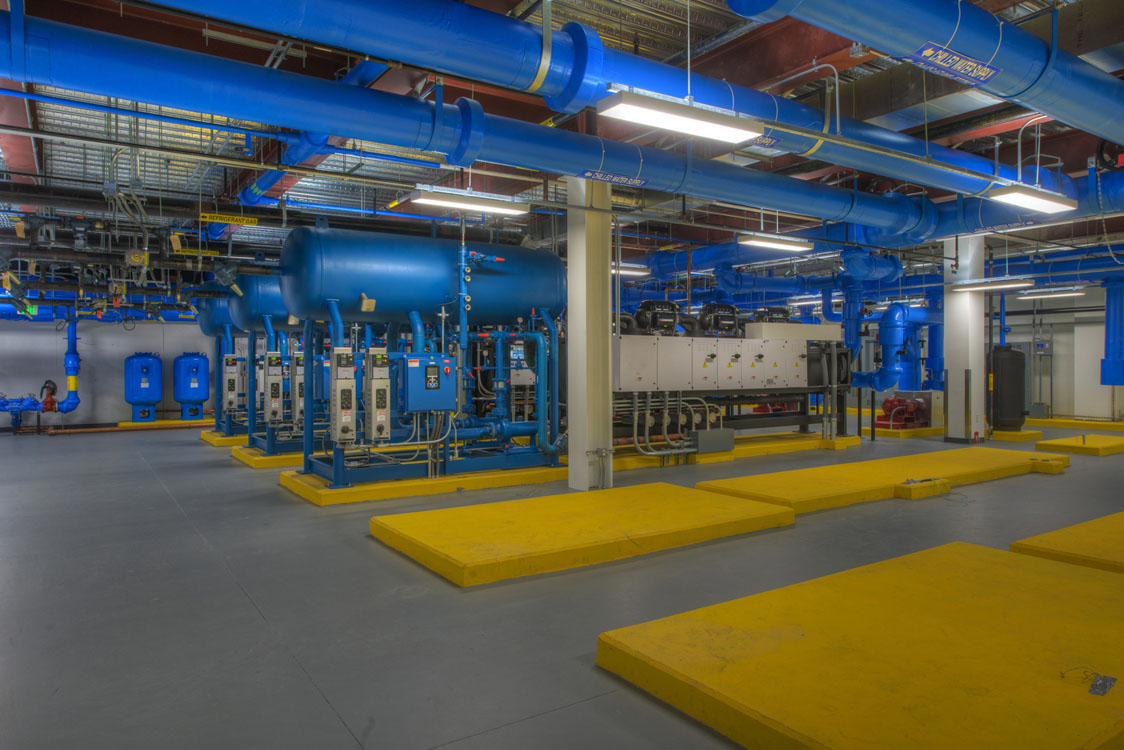 A large room with blue and yellow pipes and equipment.