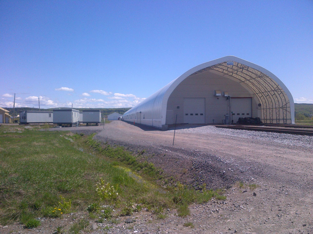 A white building on the side of a dirt road.