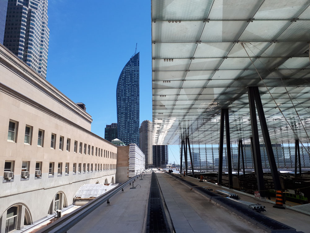 A view of a building with a glass roof and skyscrapers.