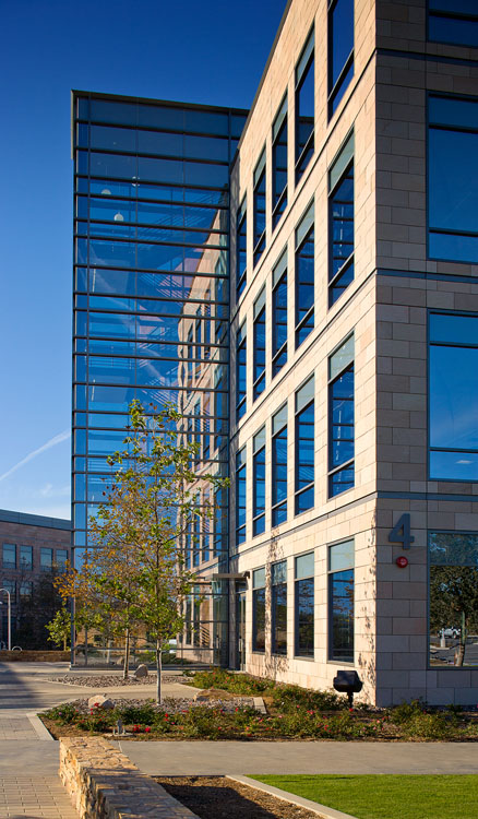 Un grand bâtiment en verre avec un espace gazonné devant.