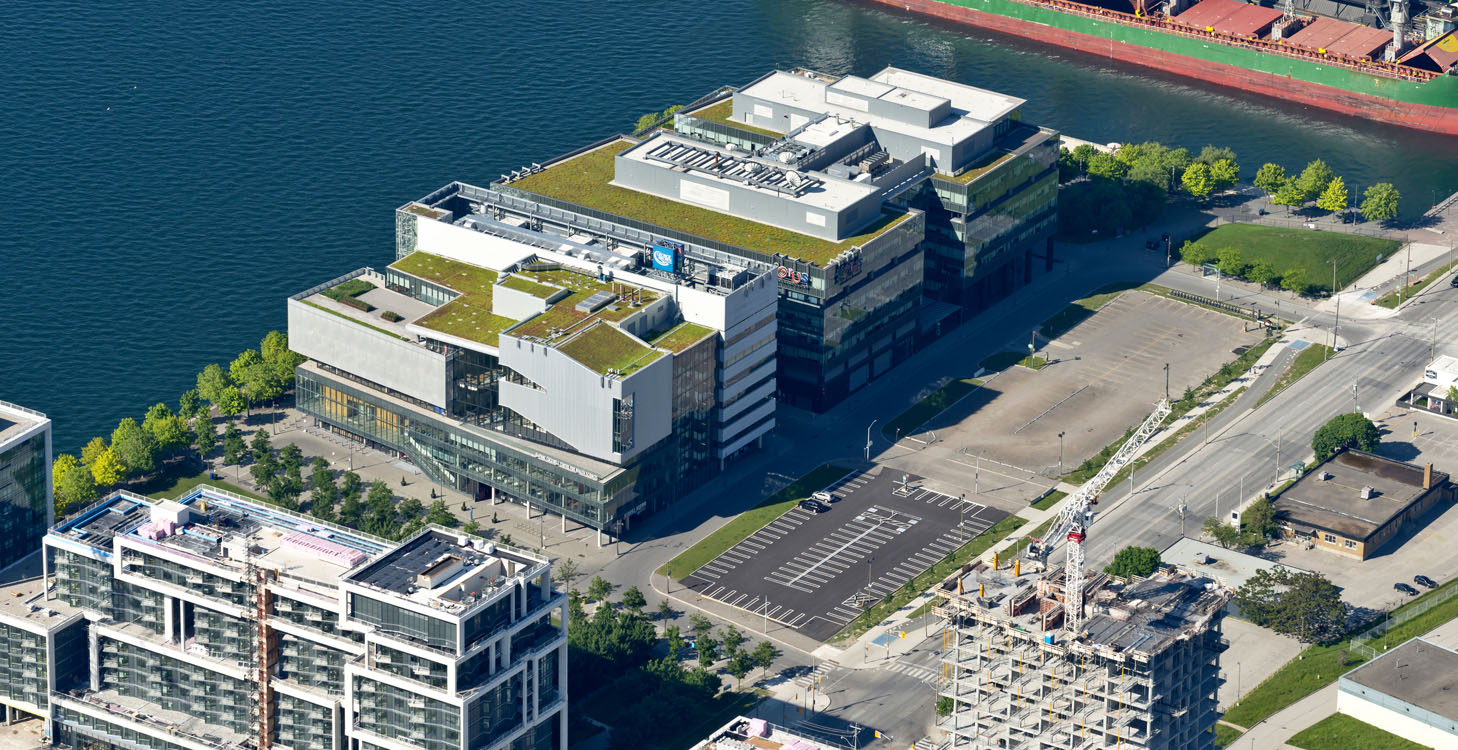 An aerial view of a building with a green roof next to a body of water.